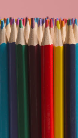 Vertical-Video-Studio-Shot-Of-Rotating-Multi-Coloured-Pencils-Against-Pink-Background